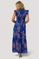 Lifestyle shot of dress in motion at sunset, showing multi-pattern indigo print, tiered hem, and versatile styling.