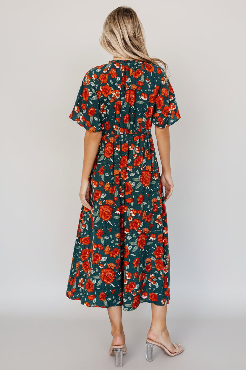 Detail shot of Polagram Botega Midi Dress fabric and print: deep jade base with orange and green floral motifs and soft rayon texture.