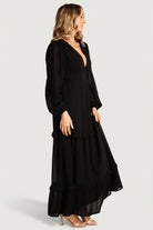Close-up of the deep V-neck bodice and ruffle tier detail on the black Bowman maxi dress, showing lining and seam finish.