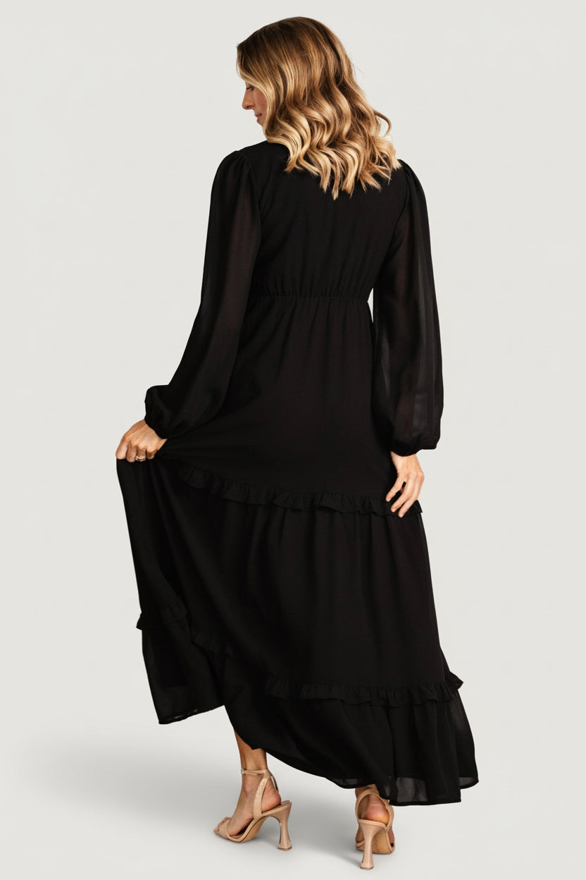Side view of the black Bowman dress emphasizing the subtle leg slit, tiered skirt movement, and lightweight polyester chiffon.