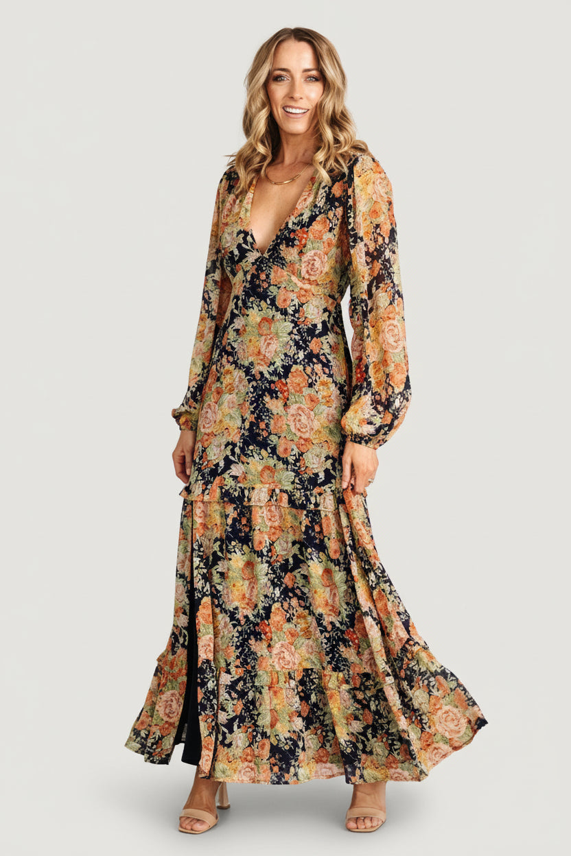 Front view of navy floral chiffon maxi dress with deep V-neck, long sleeves, elastic back waist and ruffle-tiered skirt with side slit.