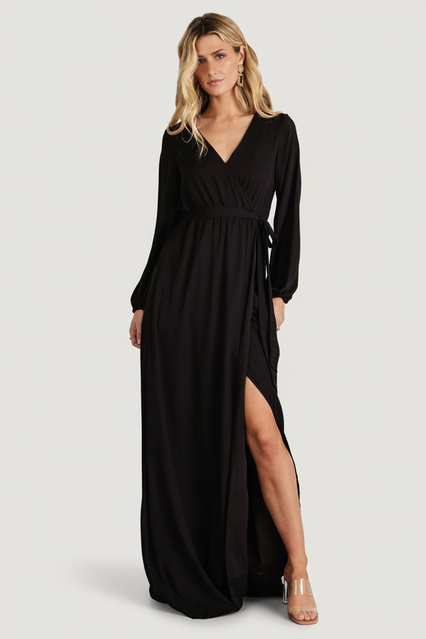 Front view of black fake-wrap maxi dress with crossover V-neck, long sleeves, elastic cuffs, and full lining, on a model.