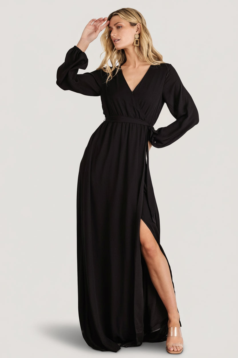 Back view of black faux-wrap maxi dress with long sleeves and maxi-length hem, shown on a model to indicate fit.