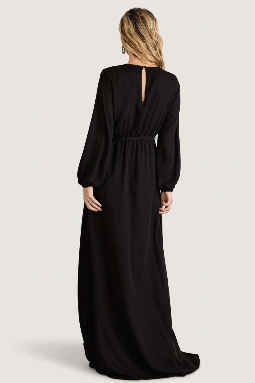 Side view of black faux-wrap maxi dress illustrating the full lining, long sleeve silhouette, and smooth fabric drape.