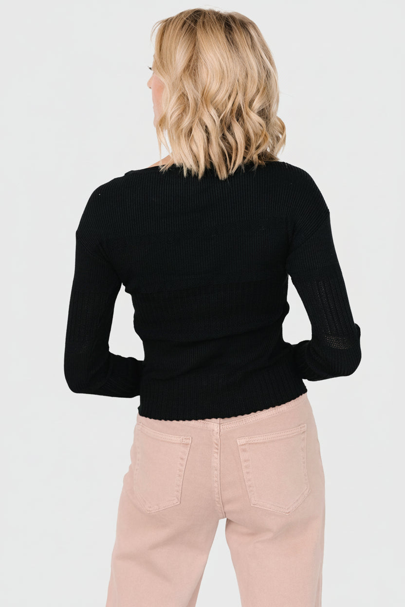 Styled outfit with black Bren sweater top paired with high-waist trousers, illustrating day-to-night versatility.