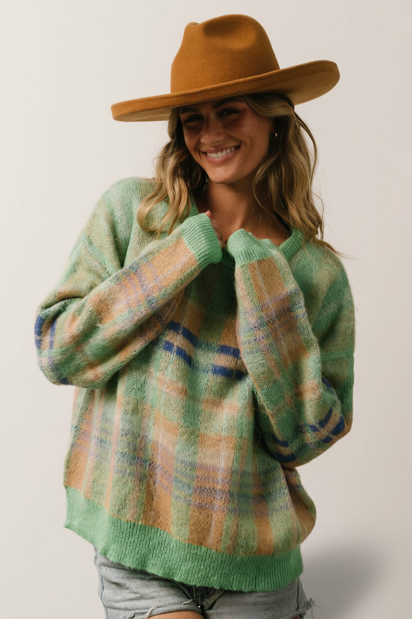 Model styling shot: green multi plaid sweater paired with casual bottoms, showing length, drop shoulder, and oversized cut.