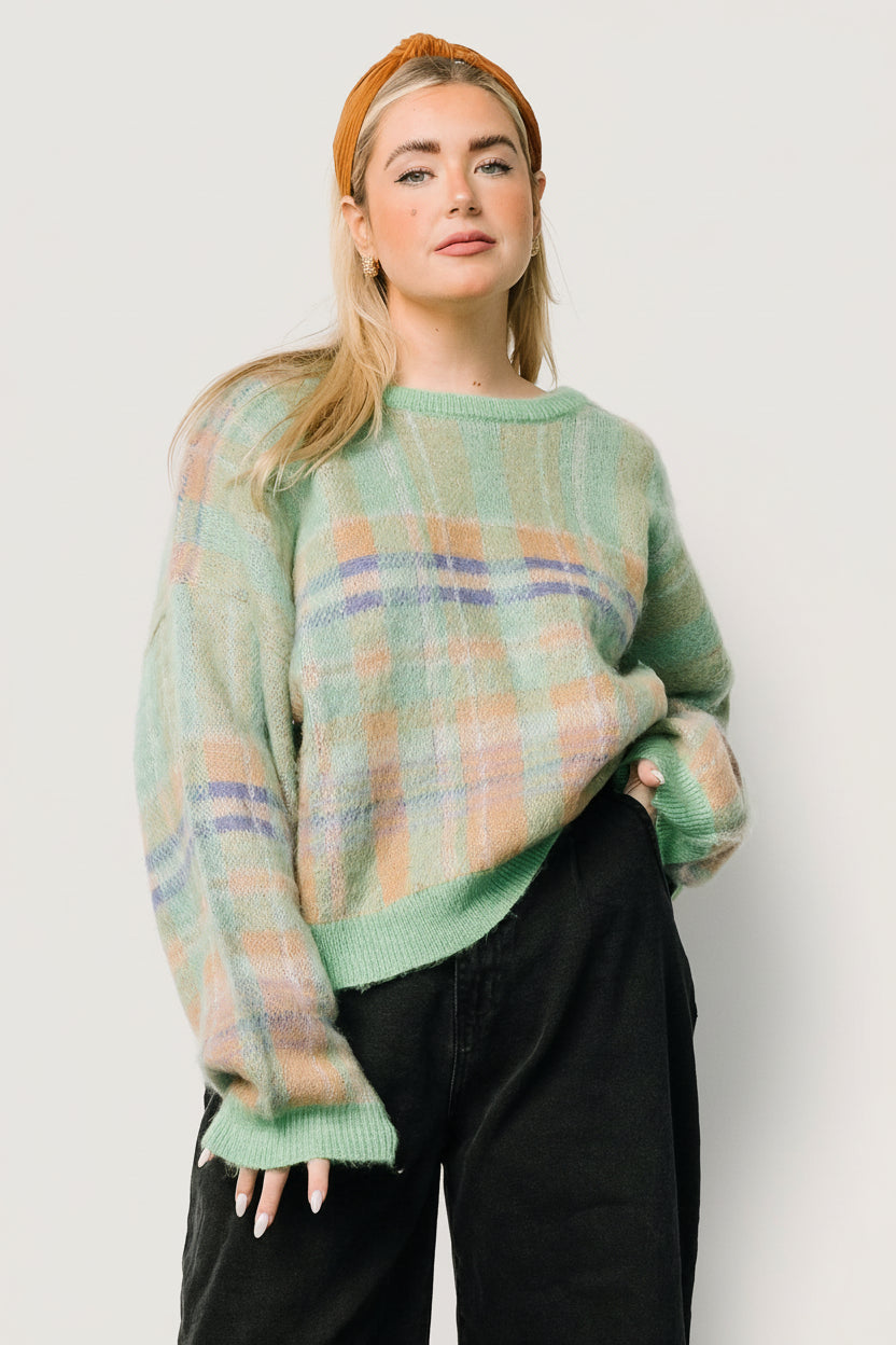 Front view of women's green multi plaid chunky knit sweater with round neckline, drop-shoulder sleeves, ribbed cuffs, and hem, on a model.