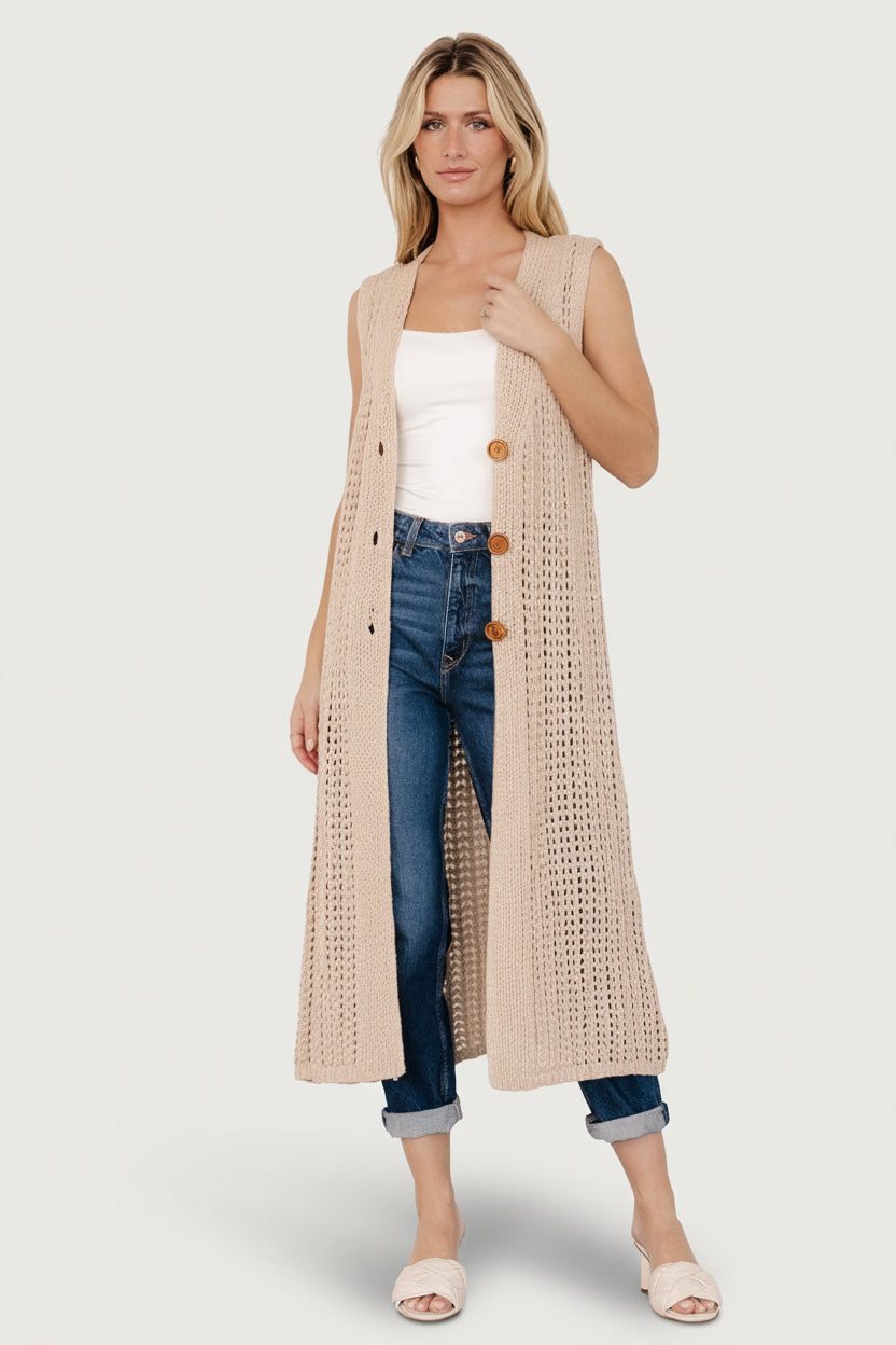 Front view: Bretta Duster Vest in natural longline chunky knit; sleeveless V-neck with three brown functional buttons.