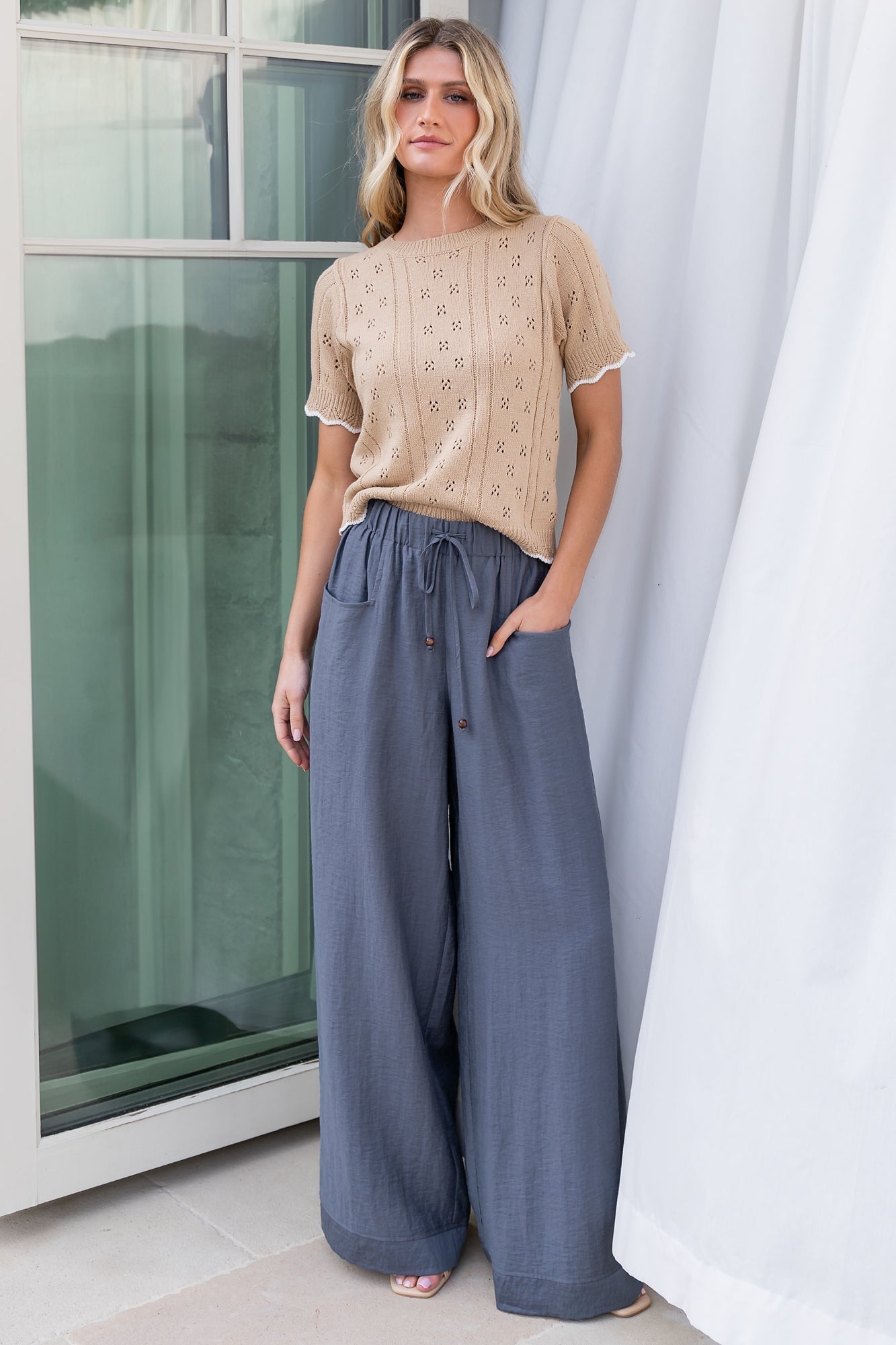 Lifestyle image of Britt Pointelle Knit Top in Natural + Ivory, showing texture, ribbed trims, and how the top layers with tailored trousers or denim.