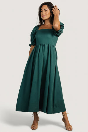 Front full-length view of Evergreen smocked midi dress on model, square elastic neckline, ruffle mid-length sleeves and visible side pockets, linen-blend.