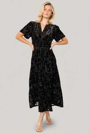 Front view of Bronwyn burnout velvet midi dress in black with notched round neckline, flutter sleeves and smocked waist.