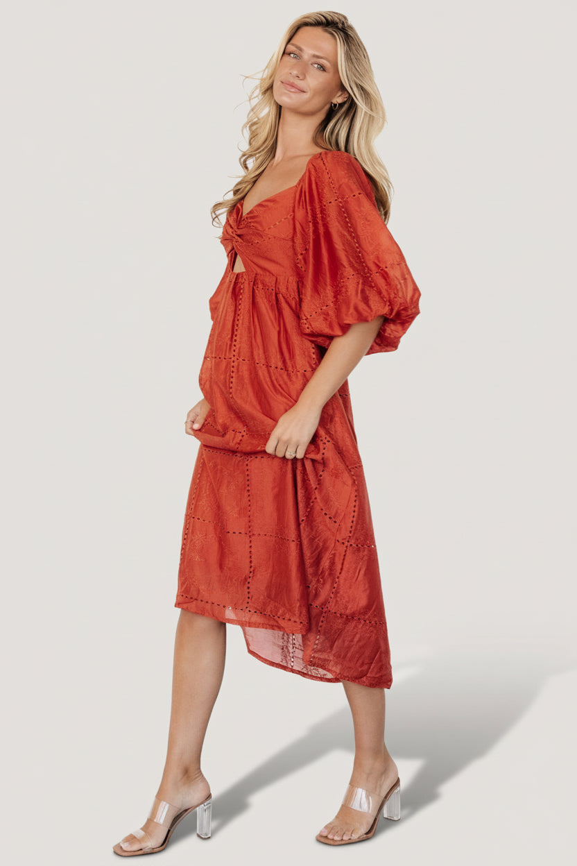 Styling view of Brynn rust midi dress paired with neutral shoes to highlight embroidered texture and midi-length hem.