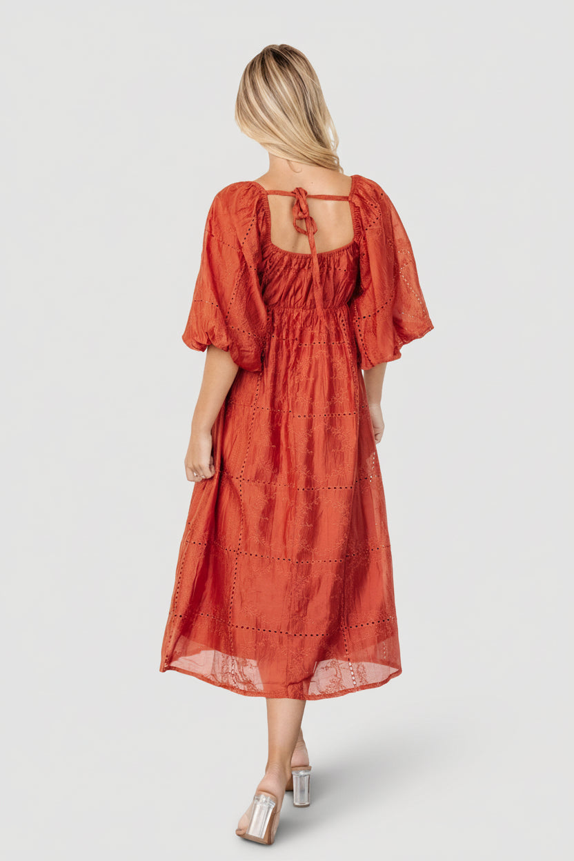 Side view of Brynn rust midi dress showing functional side pocket, fitted bodice, and fully lined skirt for smooth drape.