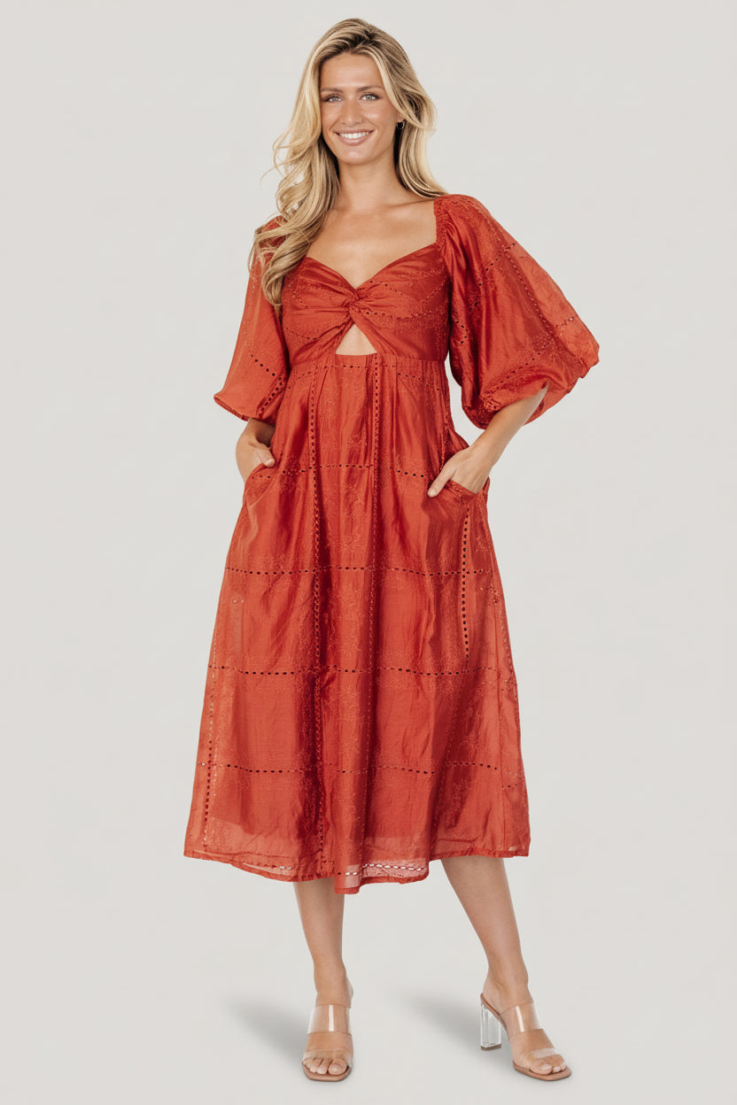 Front view of Brynn rust midi dress showing sweetheart neckline, twist bust, keyhole under-bust, tonal embroidery, and side pockets.