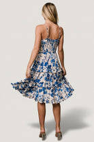 Side view showing functional side pocket and elastic waist of the Calina tiered midi dress in ivory and blue floral.