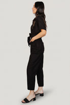 Styled outfit shot of the Dallas Button-Up Linen Jumpsuit in black, paired with neutral accessories to show everyday styling possibilities.