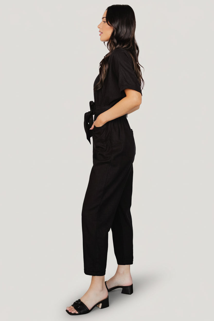 Styled outfit shot of the Dallas Button-Up Linen Jumpsuit in black, paired with neutral accessories to show everyday styling possibilities.
