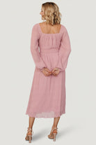 Styled look of the Dalton blush midi dress on model, emphasizing smocked waist, bloused bodice and event-ready silhouette.