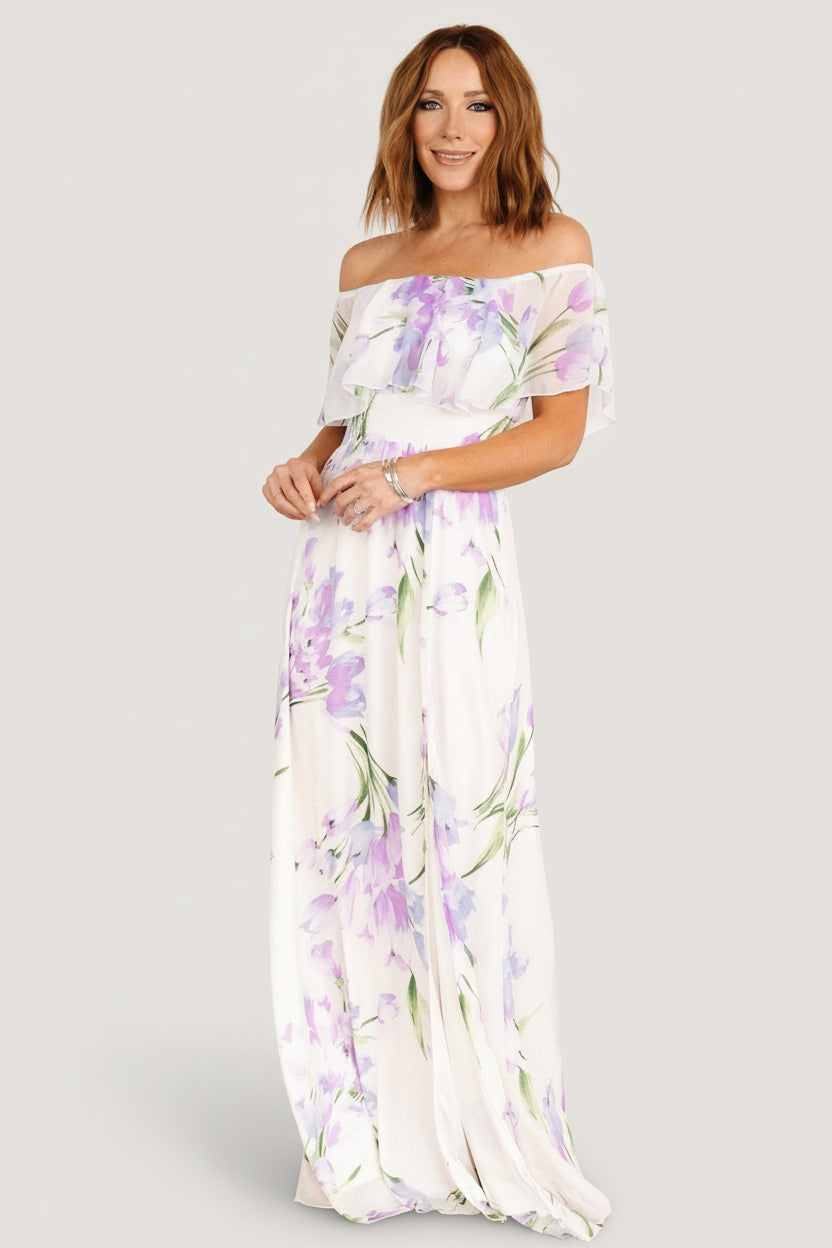 Full-length model view of Daphne maxi dress in ivory with lavender florals, styled with sandals to show length and movement.