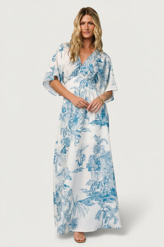 Front view of ivory maxi dress with blue tropical print on model, V-neckline, kimono sleeves, gathered under-bust yoke, and left-side slit visible.