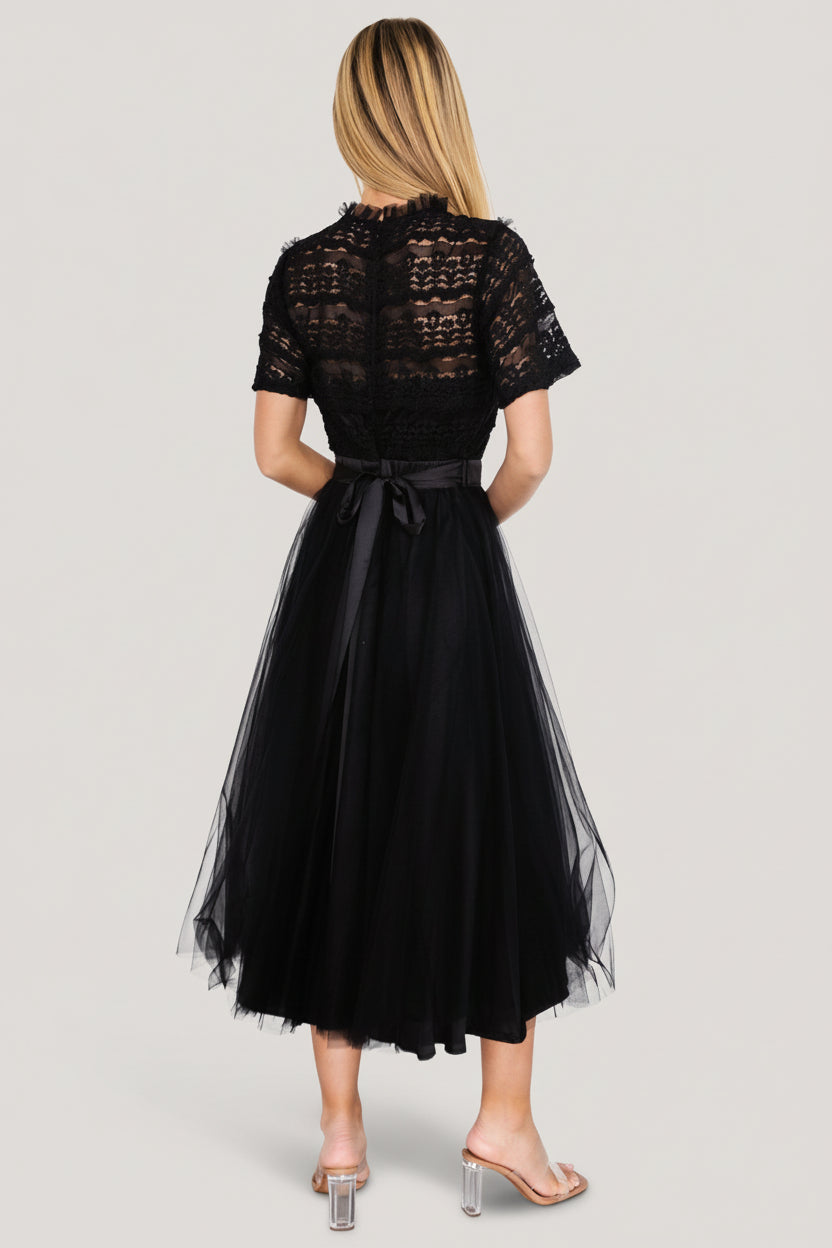 Model wearing the black tulle midi dress in a full-length shot, illustrating silhouette, sleeve length, and the dress's semi-formal styling.