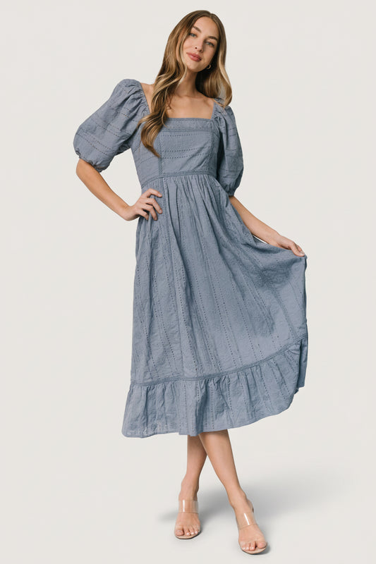 Model in dusty blue Delaney Eyelet Midi Dress — full-length view showing Florentine neckline, smocked back, and tiered skirt.