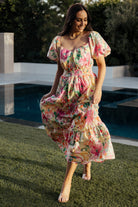 Model wearing the tiered midi dress walking, displaying skirt movement, the floral pattern, and relaxed silhouette with smocked waist.