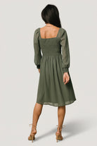 Lifestyle shot of the dark sage short dress in motion, showing sleeve movement and soft chiffon texture