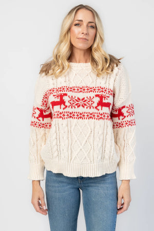 Elyse Sweater in Cream + Red with a Fair Isle reindeer and snowflake pattern, cable knit detailing, and a crew neckline.