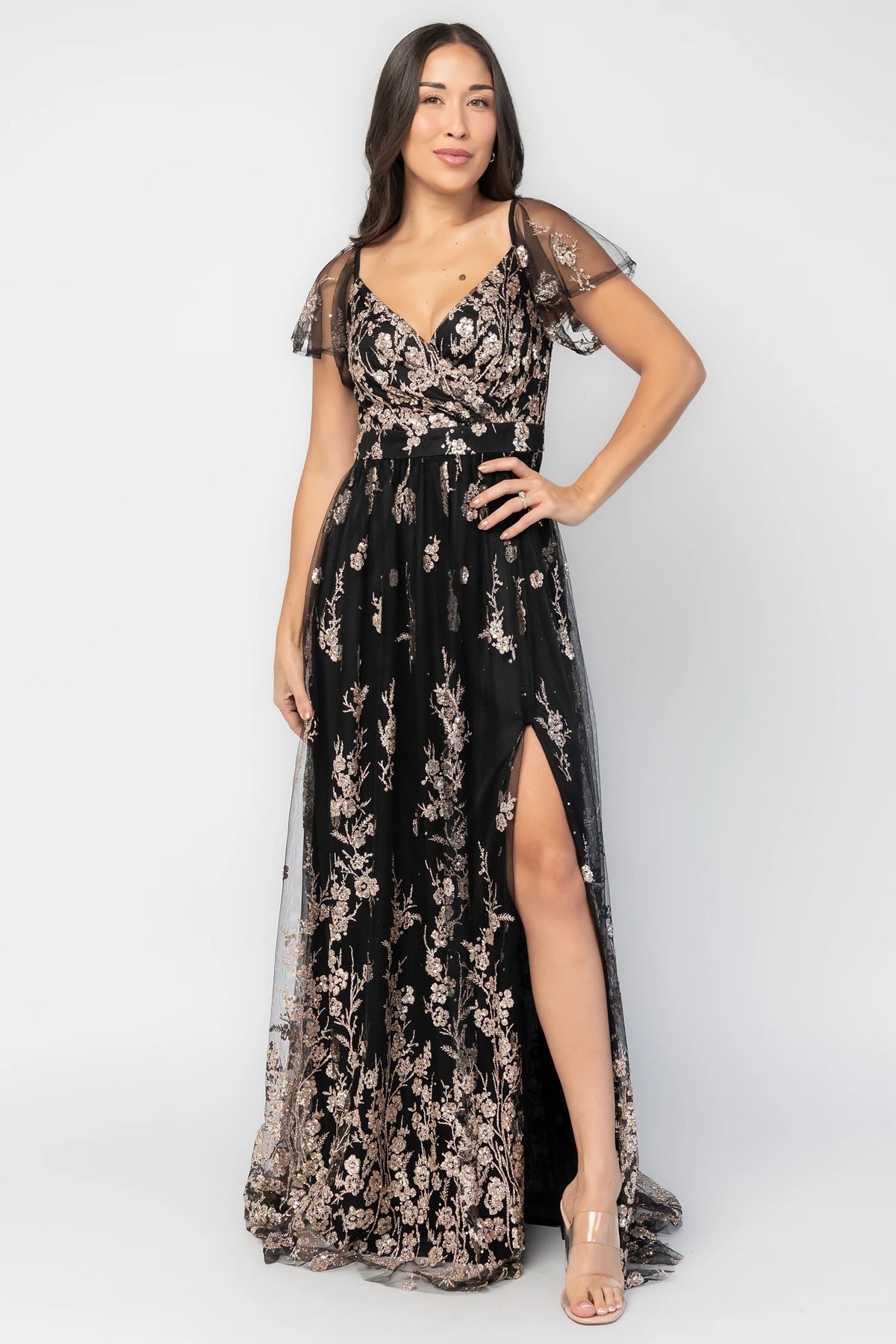 Esmerelda Shimmer Gown in Black + Rose with floral sequin embroidery, surplice V-neckline, flutter sleeves, and front slit.