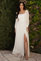 Front view of white Giselle chiffon maxi dress with smocked bodice, 3/4 sleeves, and a left thigh slit.