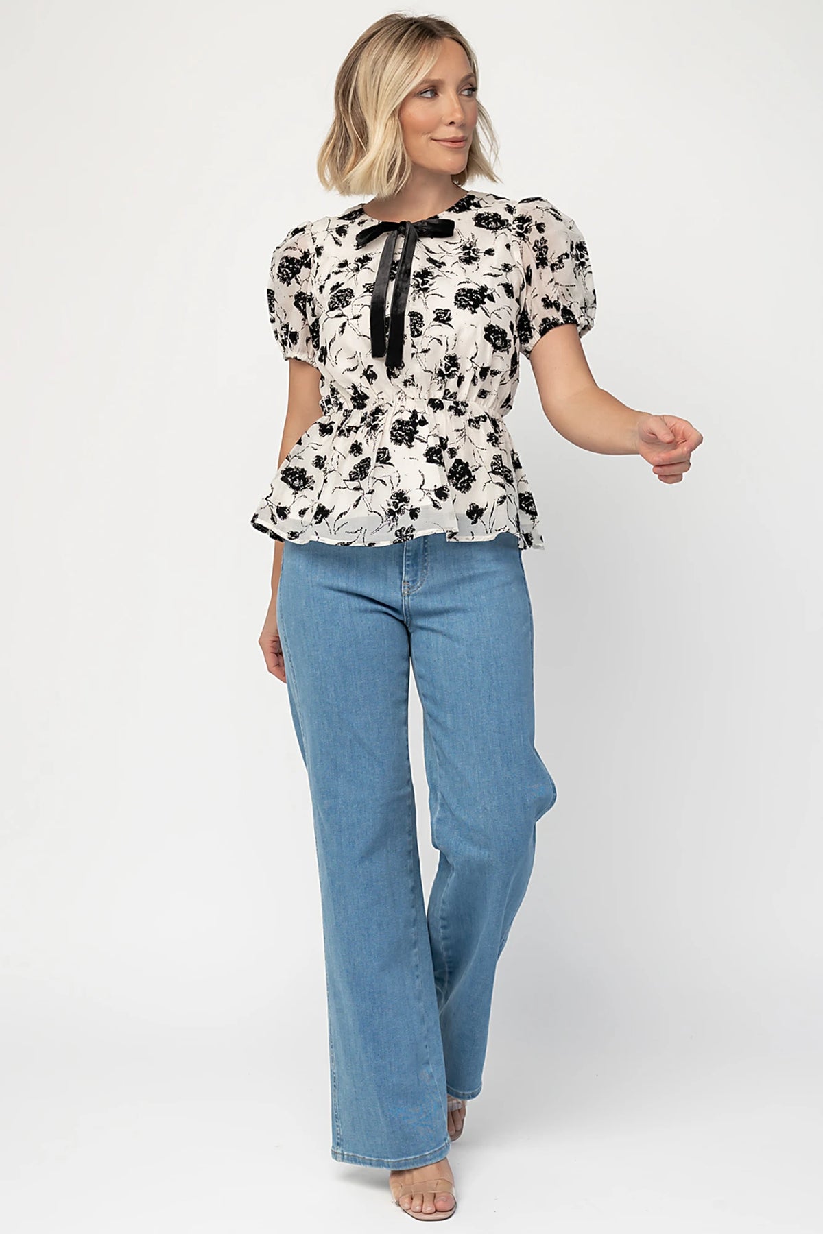 Gwenyth Peplum Blouse in Ivory + Black with velvet florals, front bow, puff sleeves, and elastic peplum waist.