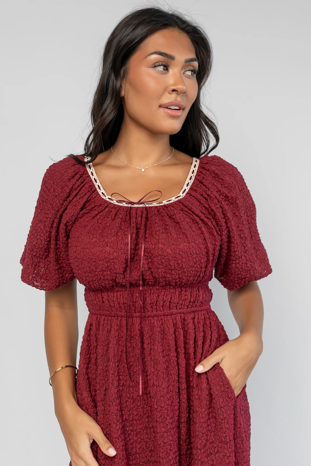 Gwyneth Short Dress in Burgundy with textured floral lace, scoop neckline, cream lace piping, and elastic sleeve cuffs.