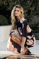 Side view of Halston one-shoulder maxi dress showing left leg slit, flowing unlined skirt, and silhouette movement in navy and blush tones.