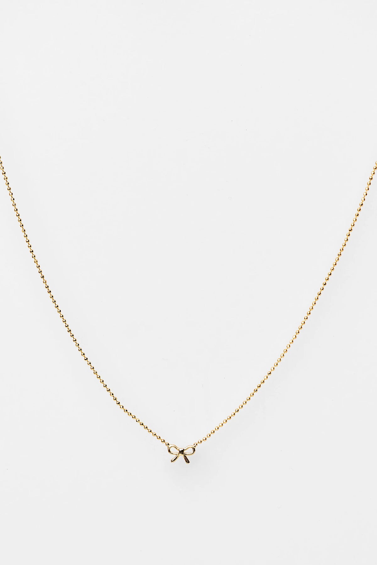 Holly Ribbon Bow Necklace in Gold with a dainty gold-tone chain and petite ribbon bow charm.