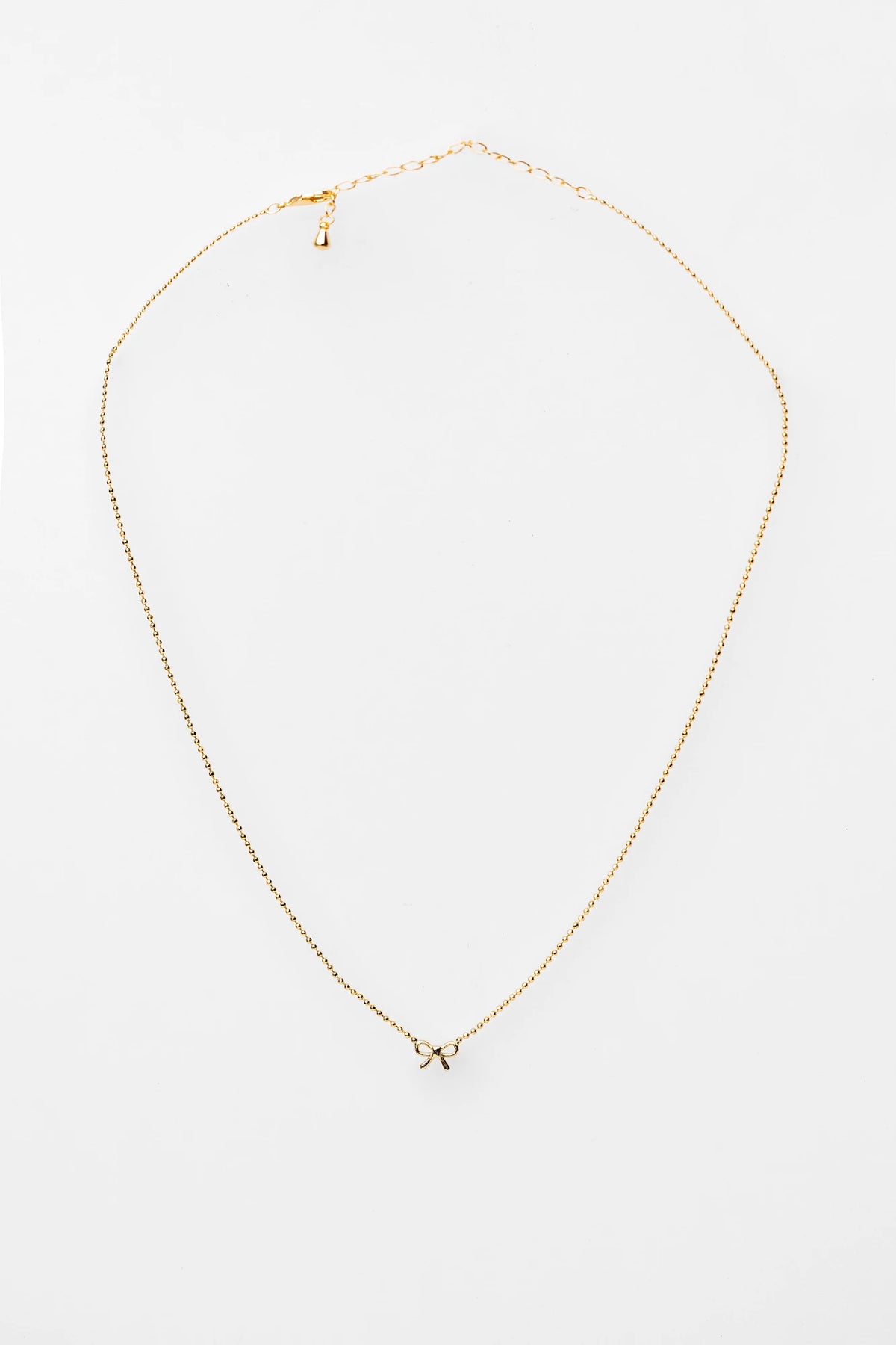 Holly Ribbon Bow Necklace in Gold with a dainty gold-tone chain and petite ribbon bow charm.
