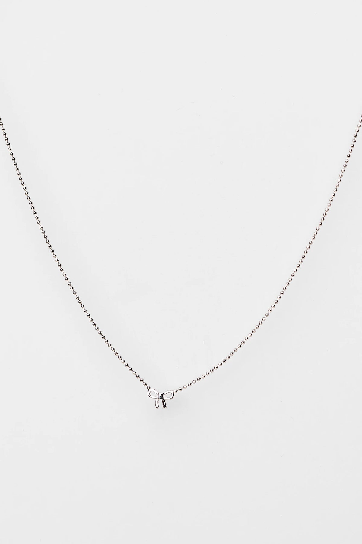 Holly Ribbon Bow Necklace in Silver with a dainty silver-tone chain and petite ribbon bow charm.
