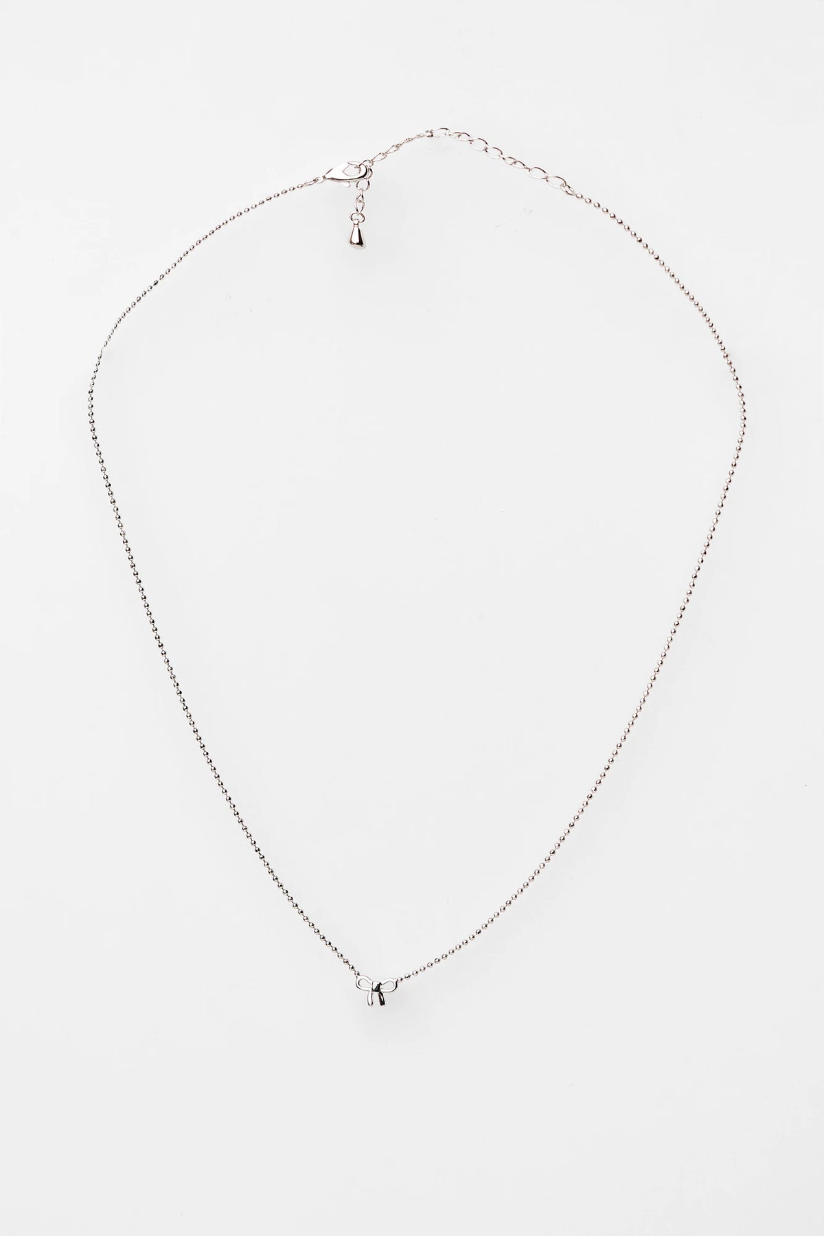 Holly Ribbon Bow Necklace in Silver with a dainty silver-tone chain and petite ribbon bow charm.
