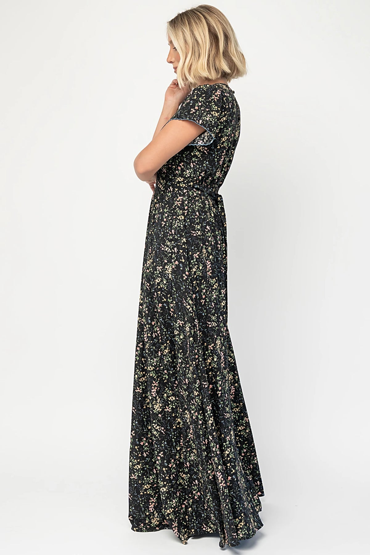 Jada Maxi Dress in Black Floral with V-neckline, blue scalloped trim, flutter sleeves, empire waist, and tie waist.