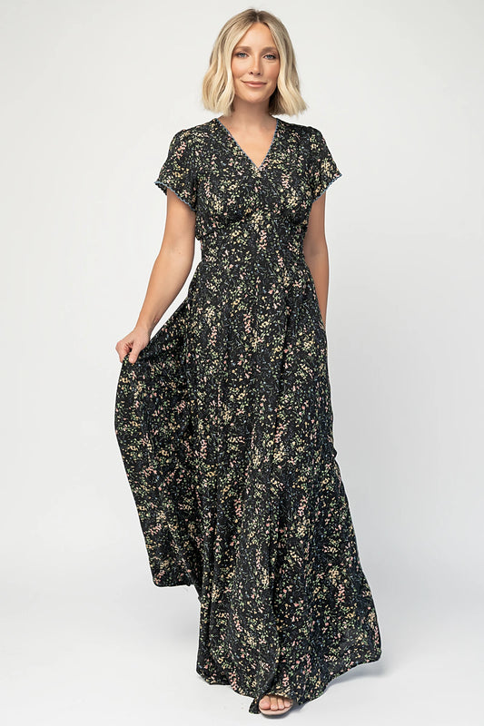Jada Maxi Dress in Black Floral with V-neckline, blue scalloped trim, flutter sleeves, empire waist, and tie waist.