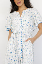 Close-up of front bodice detail highlighting lace trim, functional buttons, and blue scalloped accents on the dress.