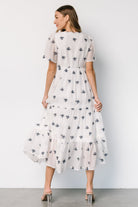 Styled outfit shot of off-white Jesenia dress with navy embroidery, illustrating midi length and flow when walking.