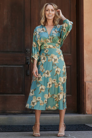 Front view of Joni Satin Midi Dress in blue multi floral print on model, V-neck, gathered bust, long batwing sleeves, midi hem (front).