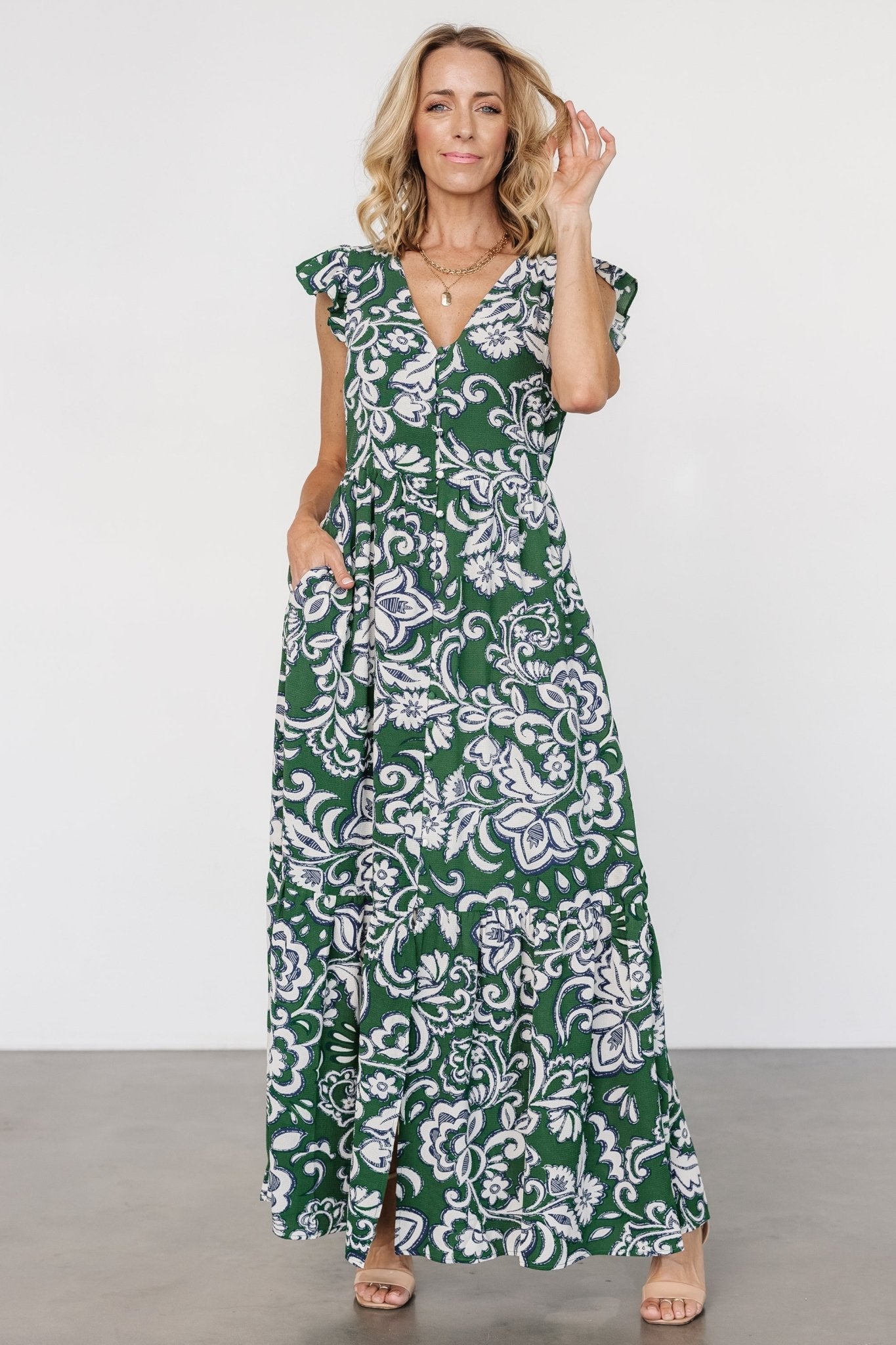 Front view of Kaia Button Maxi Dress in green botanical print on model; V-neck, cap flutter sleeves, functional front buttons, hidden pockets.