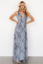 Three-quarter view of dusty blue floral tulle maxi showing bodice, tank-style sleeves, smocked waist, and layered tulle skirt movement.