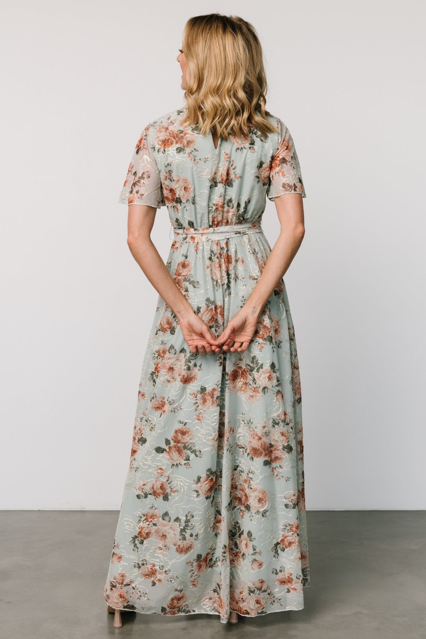 Three-quarter view of Katalaya Maxi Dress highlighting flutter sleeves, elastic-back waist, and the skirt’s graceful maxi drape in sage with gold accents.