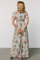 Three-quarter view of Katalaya Maxi Dress highlighting flutter sleeves, elastic-back waist, and the skirt’s graceful maxi drape in sage with gold accents.