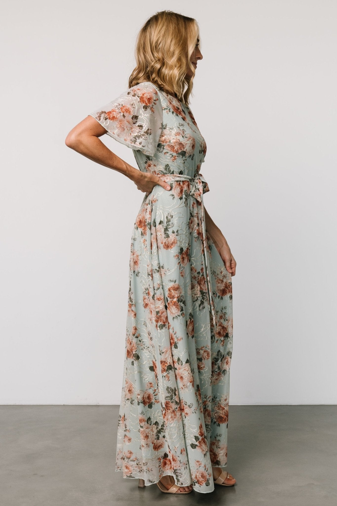 Styled detail of the Katalaya Maxi Dress sash tied at the waist with a flowing maxi skirt and delicate gold floral embroidery on sage tulle.