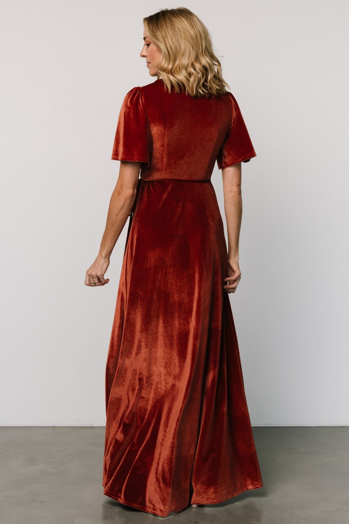Side view of the Katelyn Cinnamon velvet maxi dress showing tulip skirt silhouette, wrap ties through side loop, and sleeve length for styling reference.