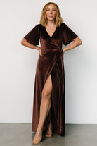 Three-quarter angle of the clove velvet wrap dress highlighting the drape, waist tie loop, and gentle stretch of the fabric on a standing model.